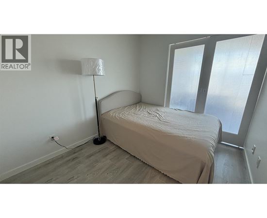 A bedroom with a bed, lamp, and sliding glass doors.