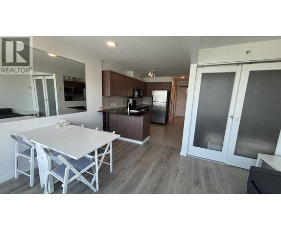 A white table and chairs are in a modern kitchen with a refrigerator and cabinets.