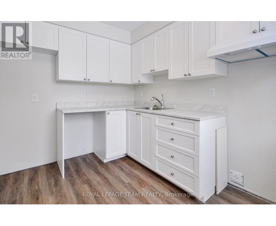 A white kitchen with a sink and cabinets.