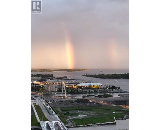 A rainbow appears over a cityscape with a bridge and waterfront.