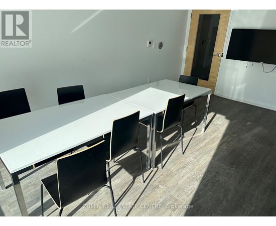 A conference room with a long white table and black chairs.