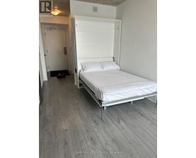 A bedroom with a bed, wooden floor and a white door.