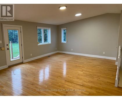 A room with wooden flooring and two windows.