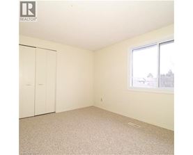 A white bedroom with a window and a carpeted floor.