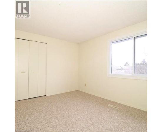 A white bedroom with a window and a carpeted floor.