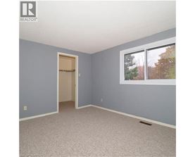 A room with a doorway leading to another room and a window with trees visible outside.