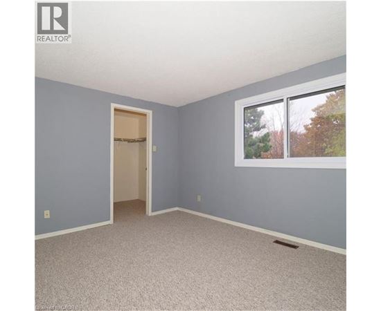 A room with a doorway leading to another room and a window with trees visible outside.