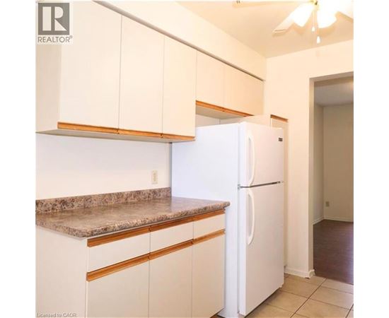 A white refrigerator in a kitchen with white cabinets.