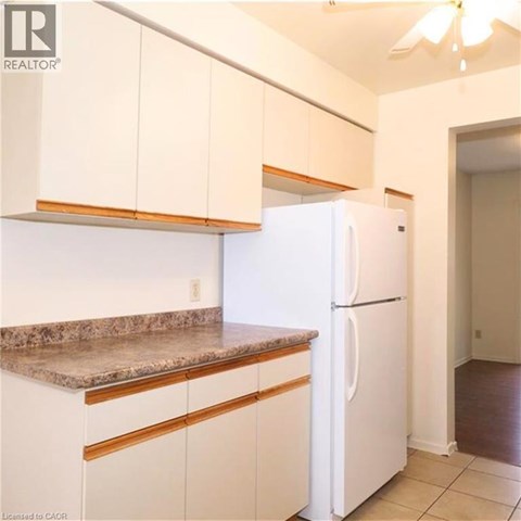 A white refrigerator in a kitchen with white cabinets.