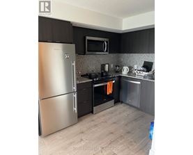 A modern kitchen with a stainless steel refrigerator and black cabinets.