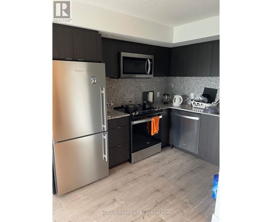 A modern kitchen with a stainless steel refrigerator and black cabinets.
