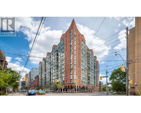 A tall red brick building with a glass facade stands in the middle of a street.