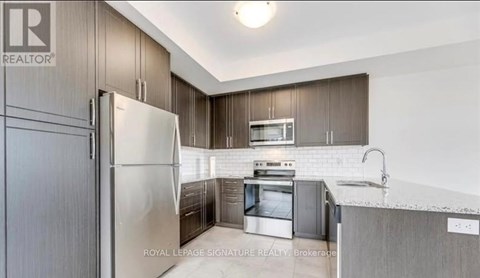 A modern kitchen with a refrigerator, oven, and sink.