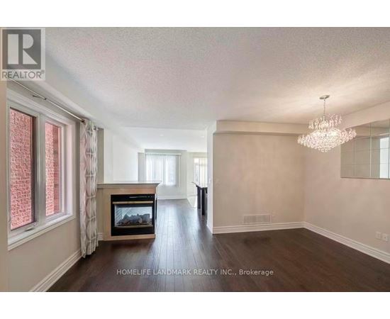 A spacious living room with a fireplace and a chandelier.