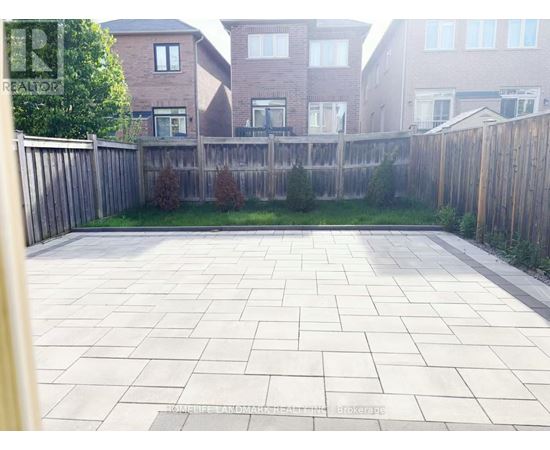A backyard with a paved patio and a wooden fence.