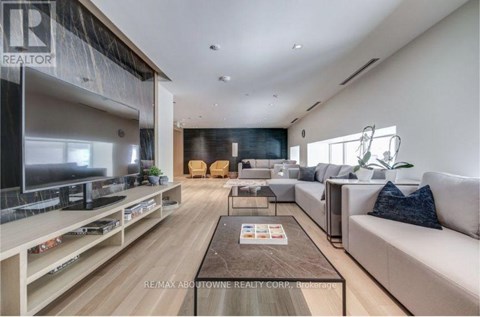 A modern living room with a large couch, a coffee table, and a flat-screen TV.