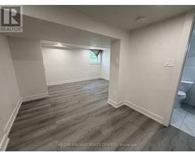 A spacious room with wooden flooring and white walls.