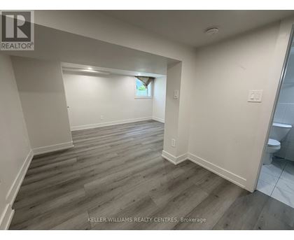 A spacious room with wooden flooring and white walls.