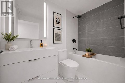 A modern bathroom with a white toilet and a grey tiled shower area.