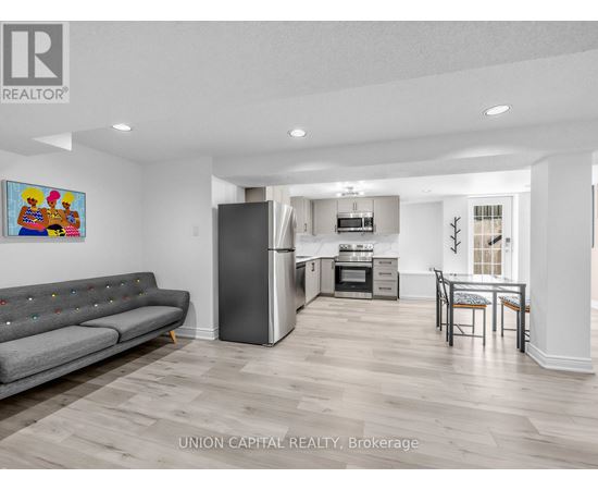 A living room with a grey couch and a painting on the wall.