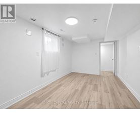 A spacious room with wooden flooring and white walls.
