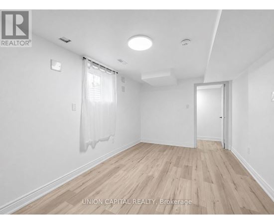 A spacious room with wooden flooring and white walls.