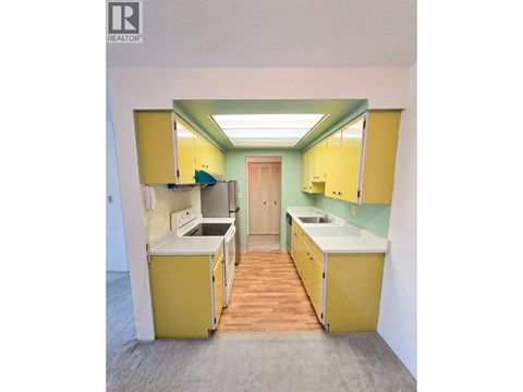 A kitchen with yellow cabinets and a green wall.