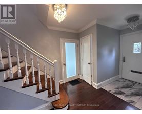 A hallway with a staircase and a chandelier.