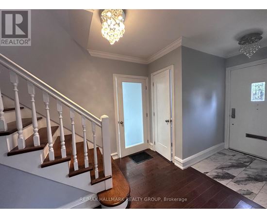 A hallway with a staircase and a chandelier.