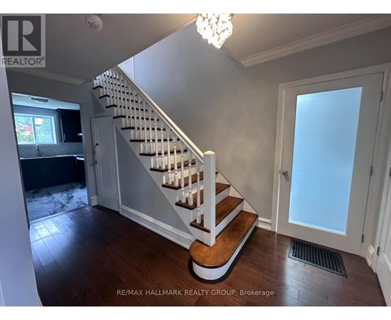 A hallway with a staircase and a chandelier.