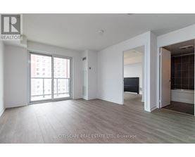 A spacious room with a large window and a door leading to another room.