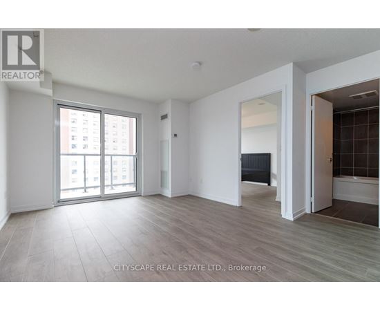 A spacious room with a large window and a door leading to another room.