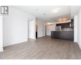A spacious room with a kitchen area in the background.