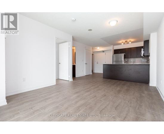 A spacious room with a kitchen area in the background.