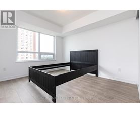 A bedroom with a large bed and a window overlooking a cityscape.