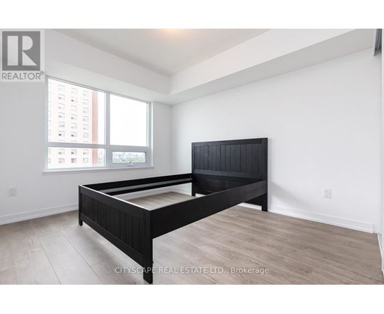 A bedroom with a large bed and a window overlooking a cityscape.