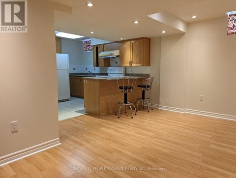 A kitchen with wooden floors and a counter with two barstools.