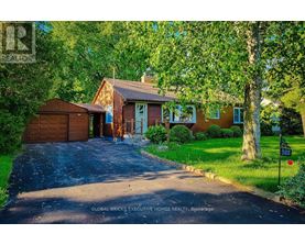 A house with a driveway and a garage is surrounded by trees.