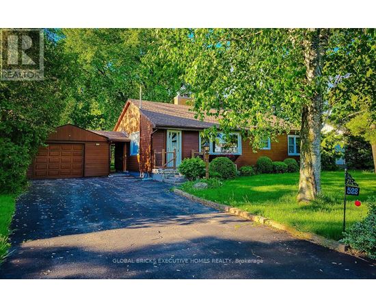 A house with a driveway and a garage is surrounded by trees.