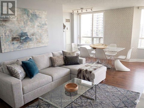 A living room with a couch, chairs, and a painting on the wall.
