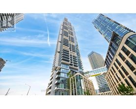 A tall, modern building with a curved glass facade stands in the foreground of a cityscape.