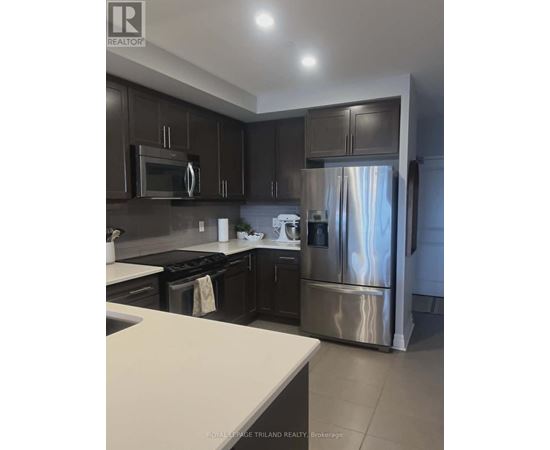 A kitchen with dark brown cabinets and stainless steel appliances.