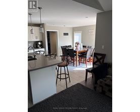 A kitchen with a bar stool and a dining table with chairs.