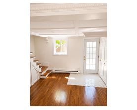 A white room with a wooden floor and a staircase.