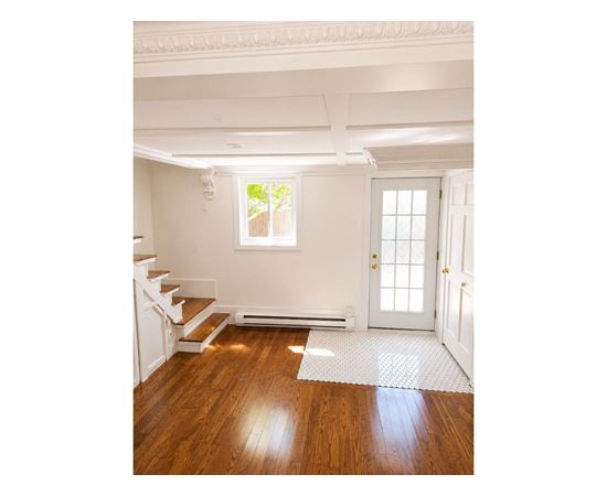 A white room with a wooden floor and a staircase.