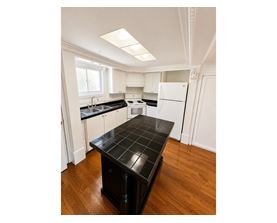 A kitchen with a black countertop and white cabinets.