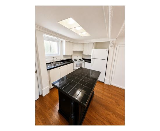 A kitchen with a black countertop and white cabinets.