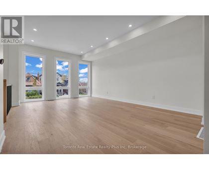 A spacious room with wooden flooring and white walls.