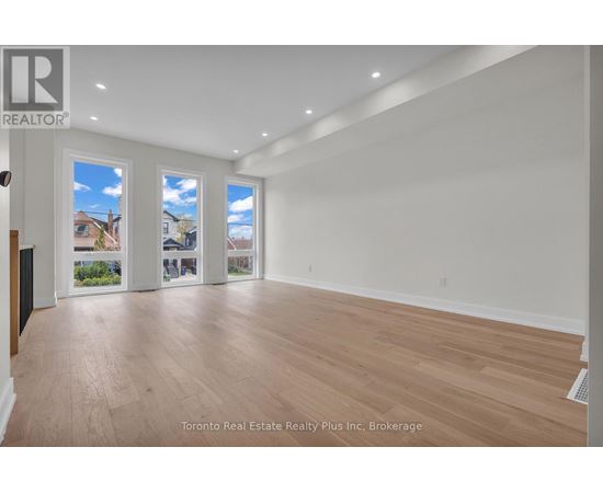 A spacious room with wooden flooring and white walls.