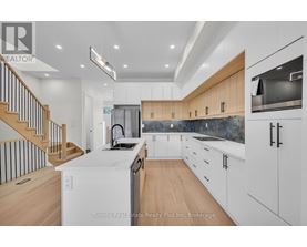 A modern kitchen with wooden cabinets and a staircase.